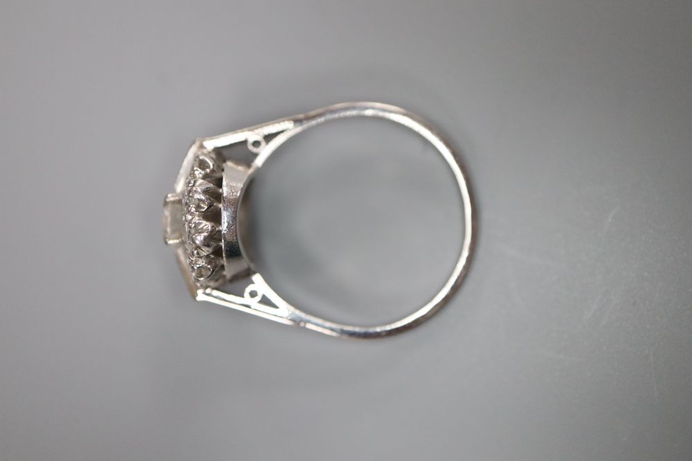 An Art Deco style 18ct white metal and diamond cluster ring, set with two baguette and nine round cut stones